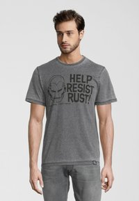 Grå bomulds T-shirt med et sort grafik af en hjelm og teksten "HJÆLP MED AT MODSTÅ RUST!" på forsiden. Rund hals og korte ærmer.