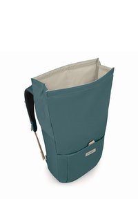 Mochila de tela color teal con un diseño estructurado, parte superior abierta, forro interior, bolsillo delantero y detalles de hardware en plata.