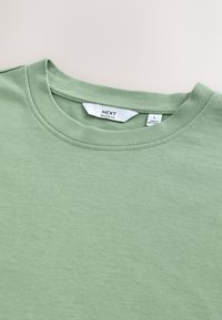 Groen t-shirt met ontspannen pasvorm, ronde halslijn, gladde textuur en label met maat L. De stof lijkt zacht en lichtgewicht.