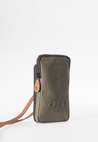 Green nylon bag with a zip closure, featuring a brown leather accent and embossed logo on the front, designed for carrying essentials.