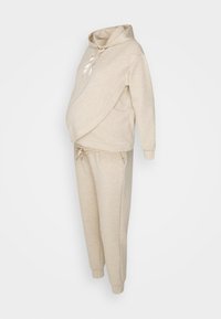 Beige graviditetsträningsoverall bestående av en hooded sweatshirt med ett crossover-design och snörning, tillsammans med tapered byxor med elastisk midja.