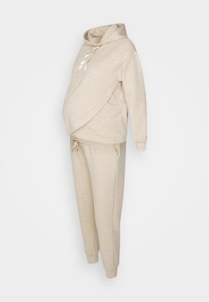 Beige zwangerschaps trainingspak met een sweatshirt met capuchon en een crossover ontwerp, gecombineerd met tapered broek met elastische taille.