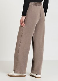 Hellbraune weit geschnittene Jeanshose aus Denim mit elastischem Bund. Der Stoff hat eine leicht strukturierte Optik und verfügt über seitliche Taschen.