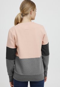 Sweat-shirt en blocs de couleurs avec des sections rose pastel, gris foncé et gris moyen. Fabriqué en mélange de coton doux, avec des poignets et un ourlet côtelés.