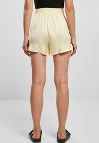 Helle gelbe Seiden-Shorts mit einem gerafften Bund und einem lockeren Schnitt, die eine glatte Textur und einen leicht ausgestellten Saum aufweisen.