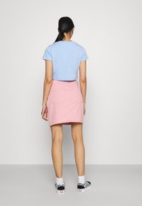 Blue cropped t-shirt, pink denim skirt, back view. Skirt has two back pockets, white sneakers with checkered pattern. Smooth textures.
