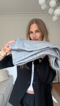 Sivý zložený sveter z textúrovaného pleteného materiálu, ktorý zdôrazňuje mäkký pocit a ležérny dizajn. Zvýraznený tmavým pozadím.