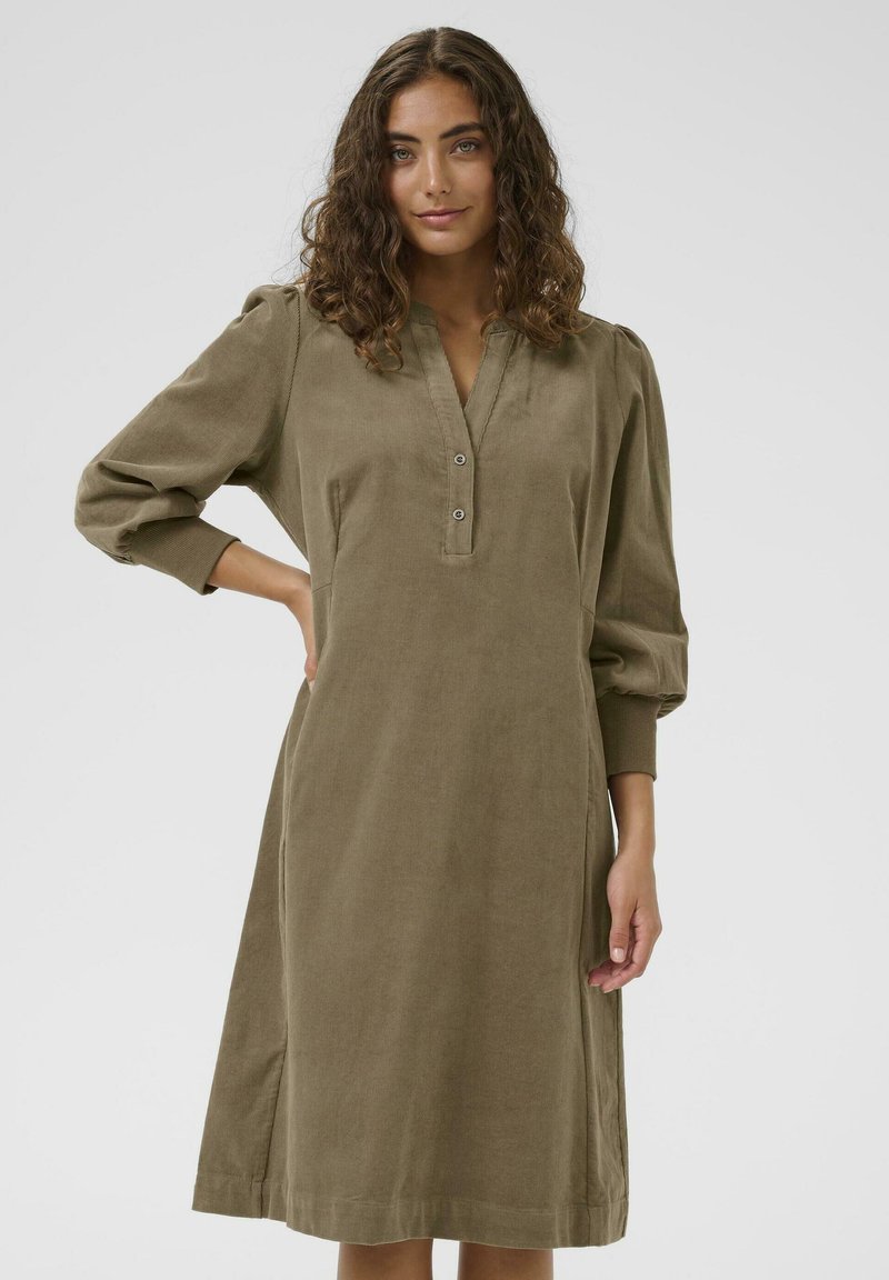 Khaki corduroy dress with a pleated design, 3/4 puff sleeves, and a V-neckline featuring two buttons. Soft texture and knee-length cut.