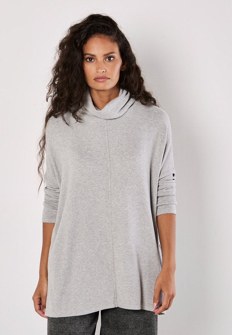 Hellgrauer Schalkragenpullover mit langen Ärmeln und lockerer Passform. Weicher Stoff, minimale Nähte und leicht seitliche Schlitze am Saum.