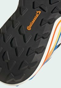 Schwarze Gummilaufsohle mit einer strukturierten, rutschfesten Musterung. Auffälliges "Continental"-Logo in Orange, mit mehrfarbigen Akzenten entlang der Kante.