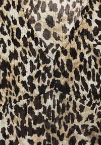 Beige fabric with black and dark brown irregular leopard print pattern and visible straight stitching details.