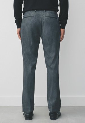 Grau gestreifte Hose mit taillierter Passform, ausgestattet mit Gesäßtaschen und einer glatten Textur, kombiniert mit schwarzen Schuhen.
