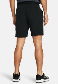 Shorts de sport negre cu un material neted, având două buzunare la spate, un talie medie și o croială dreaptă, purtați cu adidași negri.