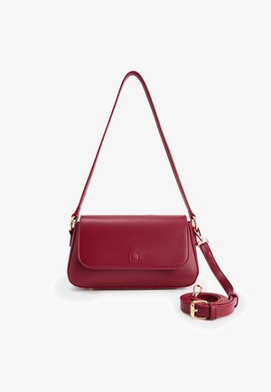 Red leather handbag with a fold-over flap, gold hardware, and an adjustable strap. Smooth texture and minimalist design.