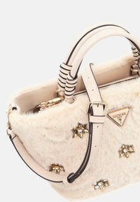 Borsa a tracolla in finta pelliccia beige con dettagli in pelle nera, caratterizzata da decorazioni floreali e una piastra logo triangolare. Manici corti e cinturino regolabile.