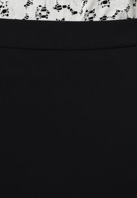 Černá sukně s hladkou texturou v kombinaci s bílým krajkovým topem s květinovými vzory, které ukazují kontrastní barvy a složité detaily.