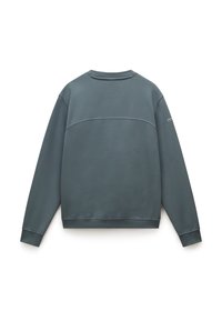 Mørk havgrønn hettegenser med rund hals, lange ermer, ribbestrikket mansjetter og nederkant. Har en sømdetalj over ryggen og minimal merkevare.