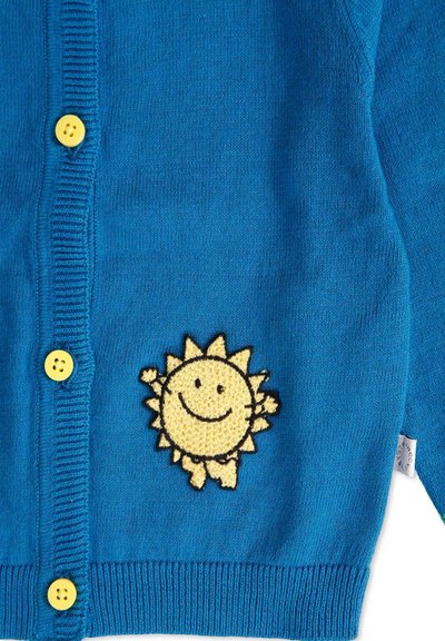 Cardigan turchese con texture a coste, caratterizzato da bottoni gialli e un ricamo di un sole sorridente in giallo e nero sul lato sinistro.