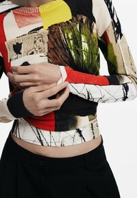 Pull en maille multicolore présentant des motifs géométriques en rouge, noir, jaune et vert. Poignets et ourlet côtelés, coupe ajustée.