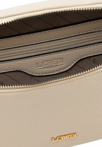Interno di una borsa in pelle beige con una tasca con zip, foderato con un tessuto texturizzato e hardware dorato. Presenta il logo impresso: "L.CREDI MUNICH."