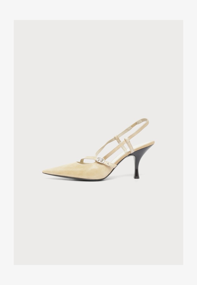Μπεζ γόβα slingback με μυτερή μύτη, λεπτά λουράκια και μια μικρή ασημένια αγκράφα στο πλάι, με μαύρο καμπυλωτό τακούνι.