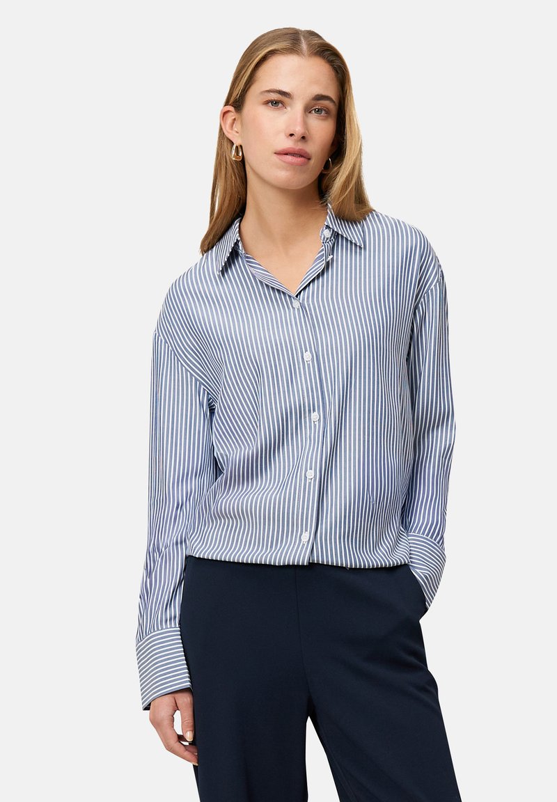 Striped button-up shirt in light blue and white with long sleeves and a relaxed fit, paired with dark pants, showcasing a casual design.