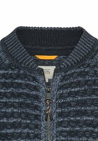 Granatowy sweter z zamkiem błyskawicznym, o teksturowanym splocie, z prążkowanym kołnierzem i widocznym zamkiem. Wnętrze ma kontrastowy, pomarańczowy akcent.