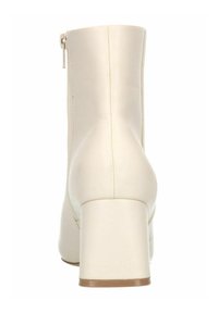 Bottine beige avec un design structuré, fermeture éclair sur le côté et un talon épais. Fini en simili cuir lisse avec de subtils détails de couture.