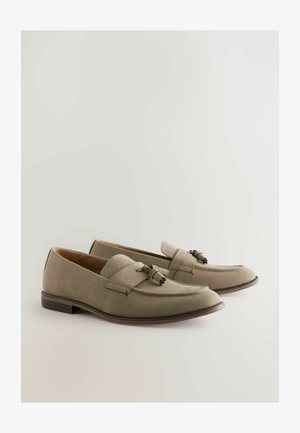 Mocassini in suede grigio con dettaglio a nappina, texture liscia, punta arrotondata e suola in pelle marrone a contrasto. Design classico slip-on.