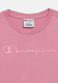 Ροζ βαμβακερό μπλουζάκι με στρογγυλή λαιμόκοψη, με ανάγλυφο κεντητό λογότυπο "Champion" σε τόνους που ταιριάζουν στο εμπρόσθιο μέρος.