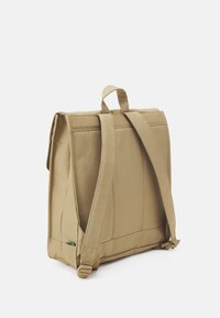 Beige messenger bag with a structured design, padded back, adjustable straps, and a green accent label. Made of durable fabric.