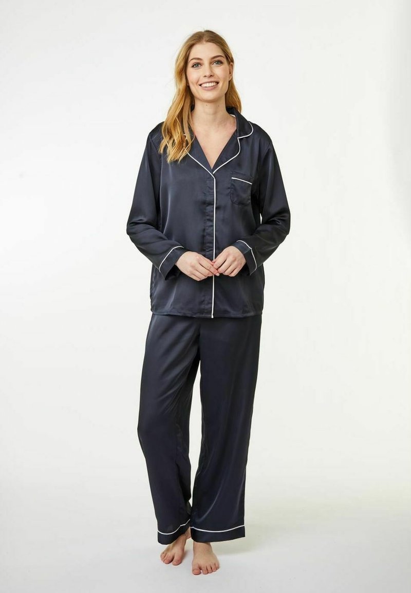 Set di pigiama in satin blu navy con piping bianco. Maglia a maniche lunghe con tasca, pantaloni abbinati con vita elasticizzata e gamba dritta.