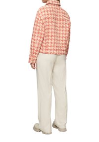 Rood en wit geruit jasje met een notch-kraag, lange mouwen en gestructureerde stof, gecombineerd met lichtgekleurde wijde broek.
