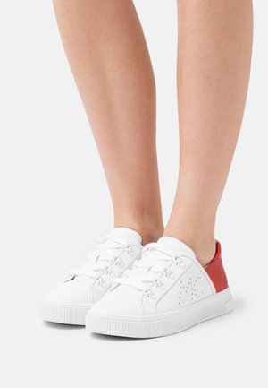 Sneakers bianche con accenti rossi, design con lacci, suola in gomma bianca testurizzata, dettagli perforati sui lati e parte superiore in sintetico liscio.