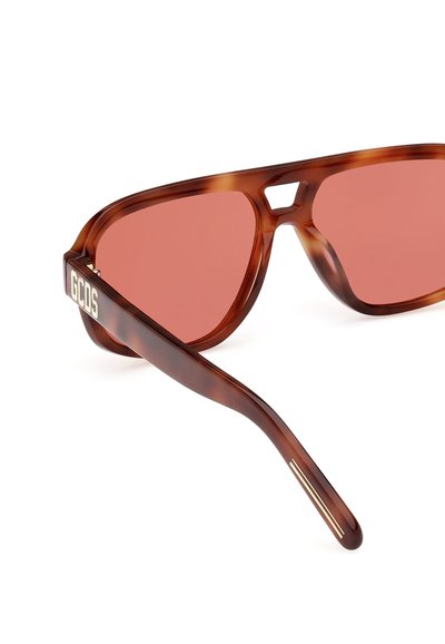 Occhiali da sole tartarugati con lenti rosa, design angolare e ponte ritagliato. Presentano un logo dorato sulla tempia e dettagli a strisce sottili.