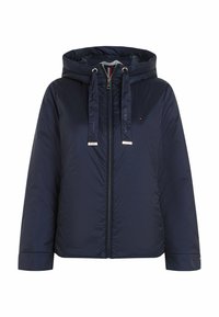Veste matelassée bleu marine avec fermeture éclair sur le devant, capuche, cordons de serrage et petit logo sur la poitrine gauche.
