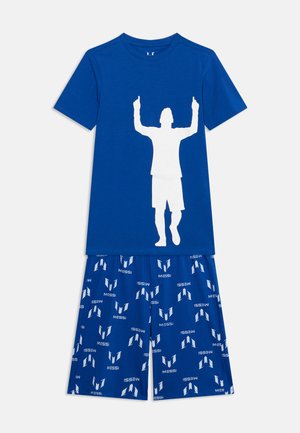 Sklop modre kratke majice s kratkimi rokavi in hlačnic, majica ima bel silhueto osebe z dvignjenima rokama, hlačnice imajo ponavljajoče se "Messi" logotipe v beli barvi.