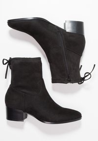Bottines en daim noir avec talon bloc, bout pointu à l'avant, fermeture éclair latérale et détail lacé en haut. Texture lisse.