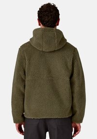Giacca in pile verde oliva con un tessuto testurizzato e caldo. Presenta un cappuccio e una vestibilità rilassata, progettata per comfort e calore.