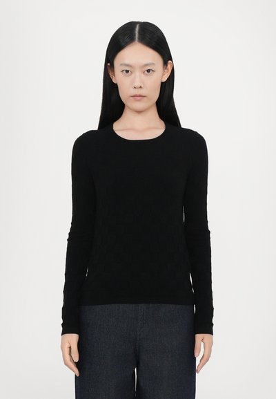 Pull noir à manches longues avec un motif texturé à carreaux. Doté d'un col rond et d'une coupe ajustée, associé à un pantalon en denim noir.
