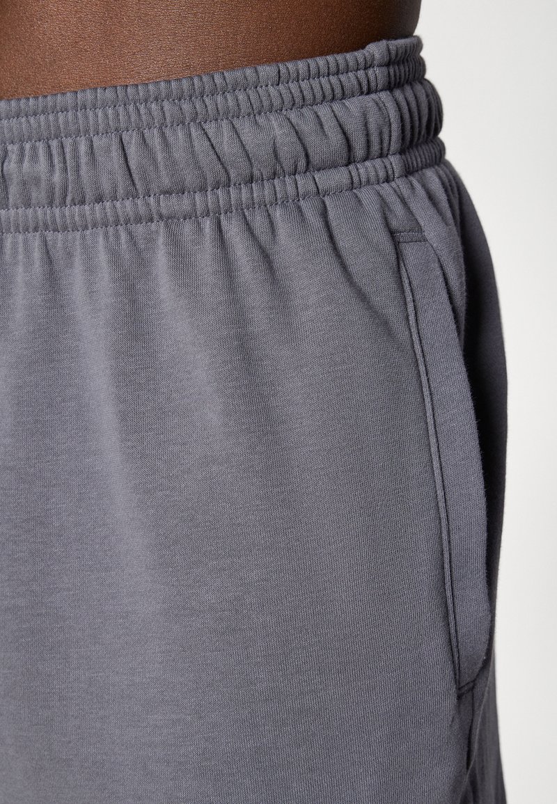 Graue Jogginghose mit elastischem Bund, seitlichen Taschen und weichem Stoff, in einer Nahaufnahme dargestellt.