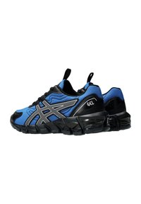 Chaussures de sport bleues et noires avec une tige texturée, arborant un logo argenté, des semelles en caoutchouc noires et une languette à l'arrière.