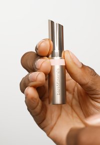 Metallinho hopeapohjainen huulipunan putkilo vaaleanpunaisella nauhalla, jossa on viisto yläosa. Tuotemerkin "bareMinerals" nimi on kaiverrettu kylkeen.