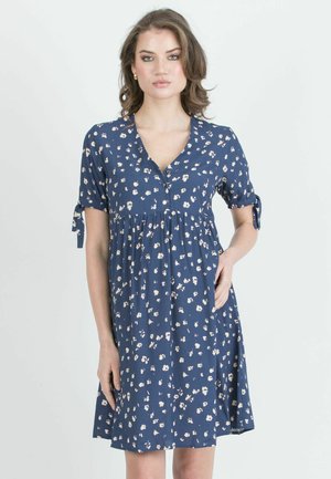 Navy blue dress with white floral print, short sleeves with ties, V-neckline, gathered waist, and knee-length hemline. Soft fabric texture.