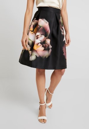 Jupe noire à motifs floraux avec des plis, fabriquée dans un tissu lisse. Présente de grandes fleurs colorées dans des tons de rose, jaune et vert.