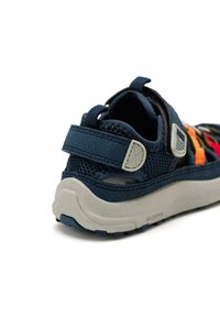 Sandalia deportiva azul marino con material de malla y sintético, tira texturizada, suela de goma, acentos multicolores y una lengüeta trasera.