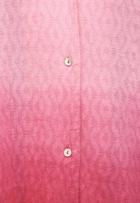 Ροζ ύφασμα με υφή σε σχήμα ρόμβου και δύο λευκά στρογγυλά κουμπιά τοποθετημένα κάθετα στο κέντρο.