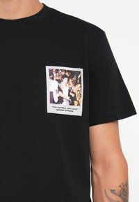 Black cotton t-shirt featuring a front pocket design with a colorful printed image and text: "F*** Football Let's Dance" - Weekend Offender.