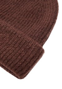 Brązowa prążkowana dzianinowa czapka z wełny z podwiniętym mankietem, zbliżenie na fakturę tkaniny.