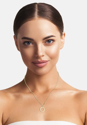 Goldkette mit einer zarten Kette und einem strukturierten, kreisförmigen Anhänger, auf einem neutralen Hintergrund präsentiert, der ihre Einfachheit betont.